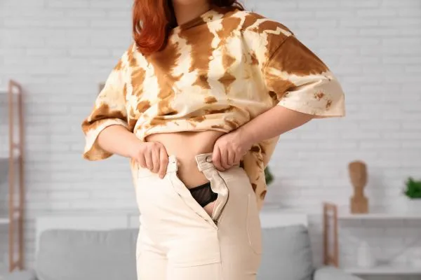 Image of woman trying to do her trousers up after pregnancy weight gain Handsworth Wood