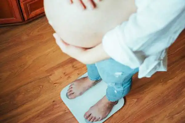 Image of woman weighing herself and experiencing weight gain through pregnancy Handsworth Wood